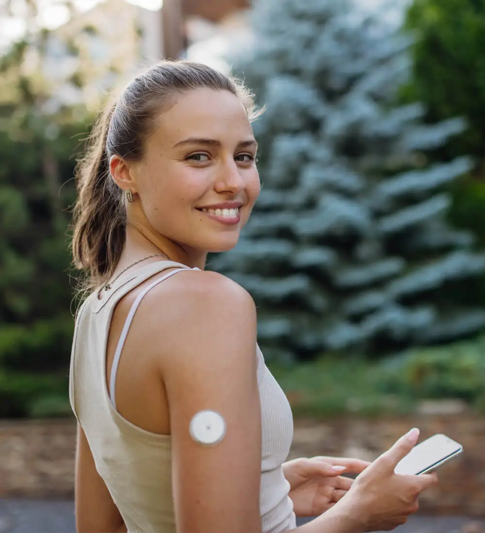 Young woman with CGM checking her blood sugar level before exercising